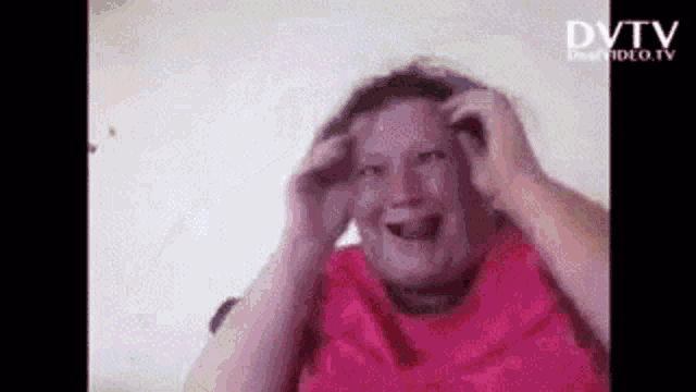 a woman in a pink shirt is making a funny face while holding her hair .