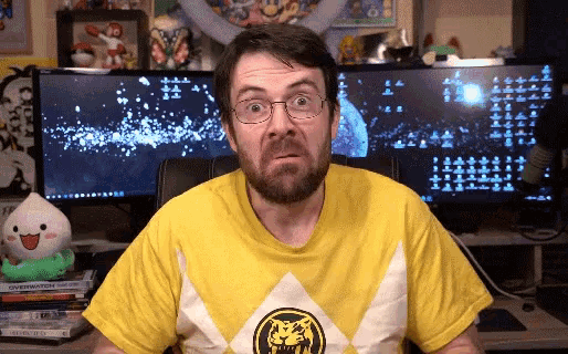 a man wearing a yellow and white power rangers shirt looks surprised
