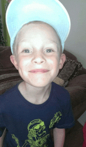 a young boy wearing a hat and a blue shirt with a skeleton on it