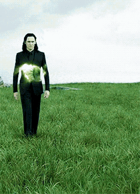 a man in a suit is standing in a field of tall grass