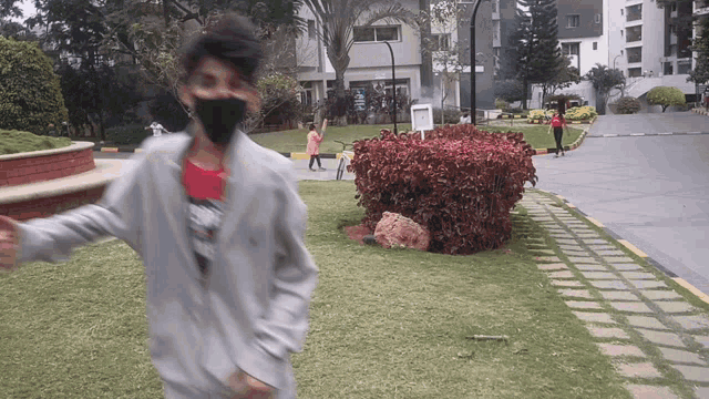 a boy wearing a black mask runs in a park