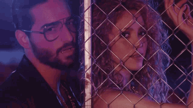 a man and a woman behind a chain link fence .