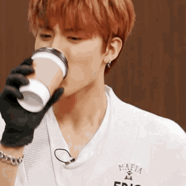 a man wearing a white shirt with the word mafia on it drinks from a cup