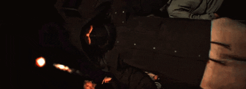 a man in a hooded jacket is laying on the ground in the dark