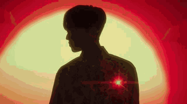 a silhouette of a man standing in front of a red and yellow light .