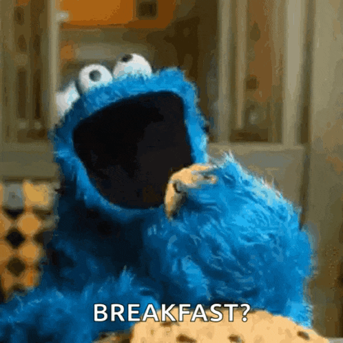 cookie monster from sesame street is eating a cookie and saying breakfast .