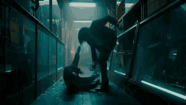 a man in a suit is kicking another man in a dark room