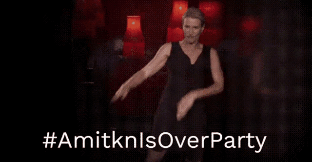 a woman in a black dress is dancing in a dark room with the words # amitknlsoverparty above her