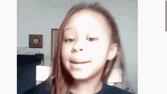 a young girl with dreadlocks is making a funny face while looking at the camera .