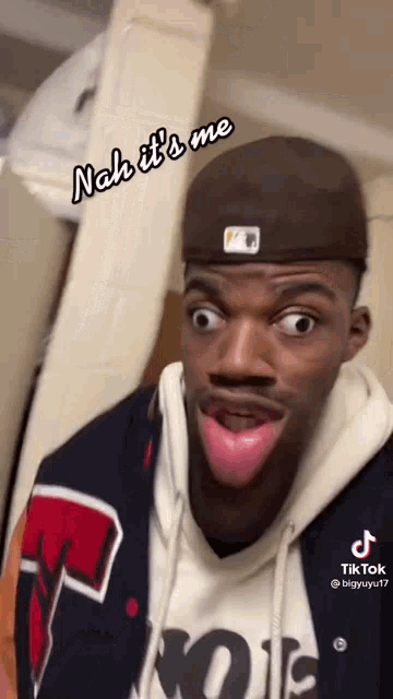 a man wearing a hat is making a funny face with his tongue out .