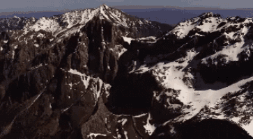 an aerial view of a mountain range with snow on the peaks