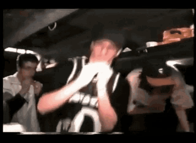 a group of people are standing in a dark room and one of them is wearing a black and white jersey with the letter n on it