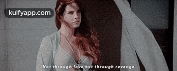 a woman with long red hair is standing in front of a window with a quote .