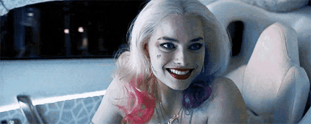 a woman with white hair and pink and purple hair is smiling while sitting in a bathtub .