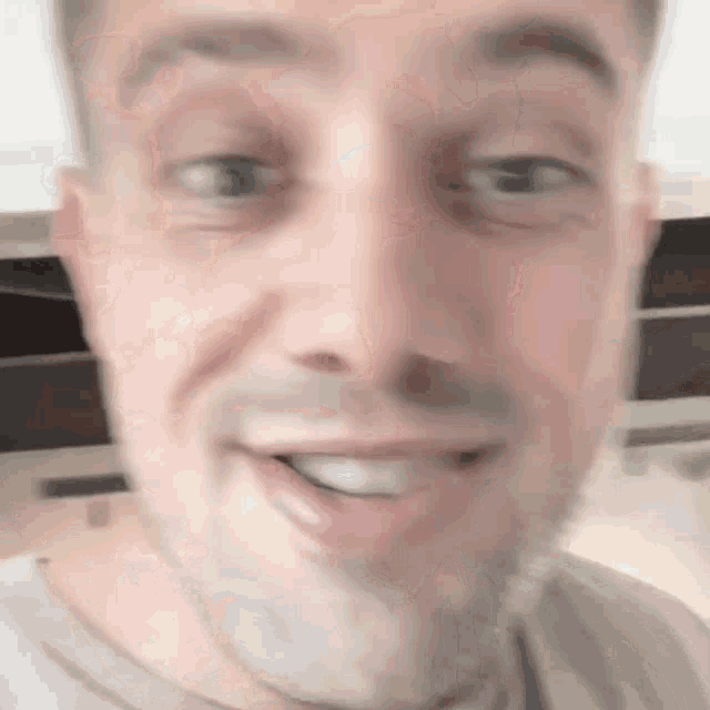 a close up of a man 's face with his mouth open and his eyes looking at the camera .