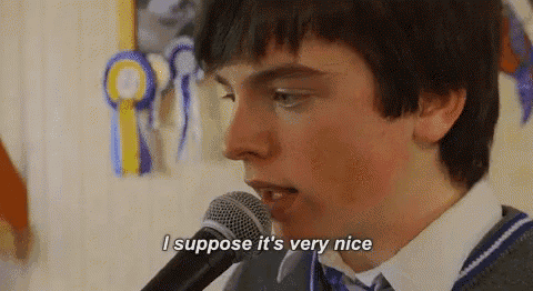 a boy is singing into a microphone and saying i suppose it 's very nice