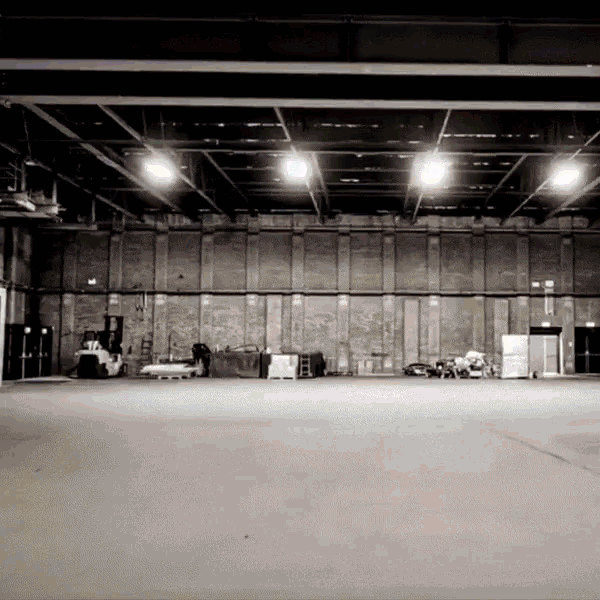 a black and white photo of an empty warehouse with a forklift in the background