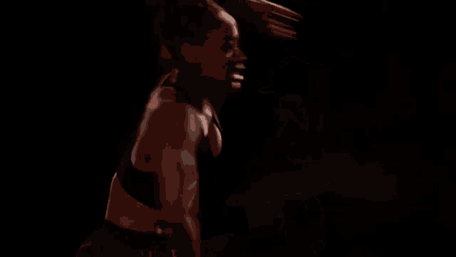 a woman with red hair is standing in a dark room with her arms outstretched .