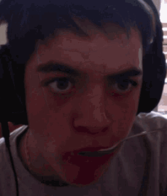 a man wearing headphones looks at the camera with a serious look on his face