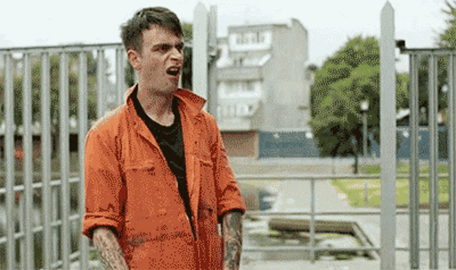 a man in an orange jumpsuit is standing in front of a fence