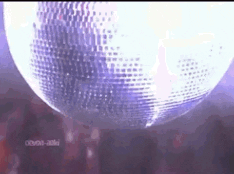 a disco ball is spinning in the air in front of a crowd .