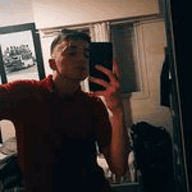 a young man is taking a selfie in a mirror .