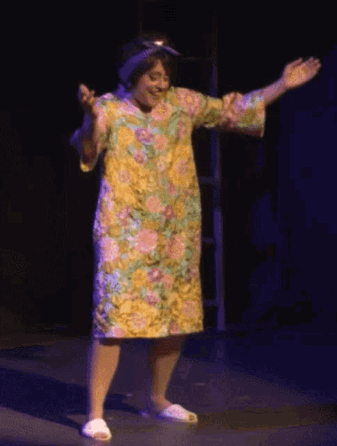 a woman in a floral dress and white slippers is dancing on stage