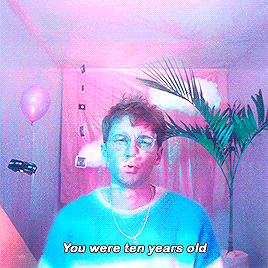 a man wearing glasses and a blue shirt is standing in front of a palm tree and balloons and says you were ten years old