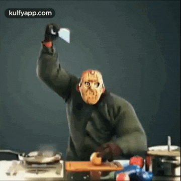 a man in a jason voorhees mask is cutting an apple with a knife .