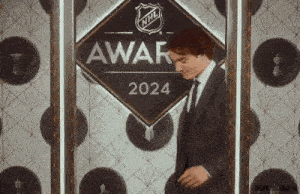 a man in a suit and tie is standing in front of a sign that says nhl awar 2024 .