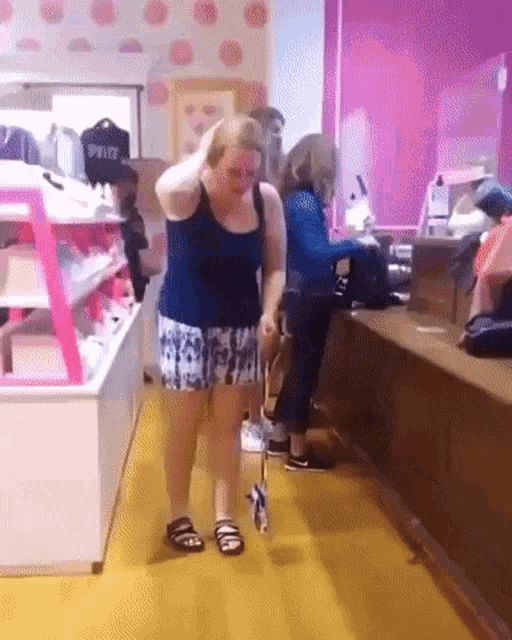 a woman in a blue tank top and shorts is walking a dog in a store