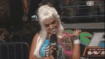 a woman in a wig holds a microphone in front of a sign that says i love sports