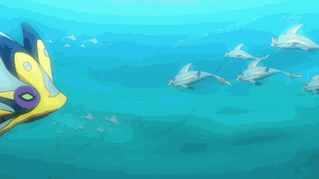 a group of dolphins are swimming in the ocean with a yellow and purple fish in the foreground