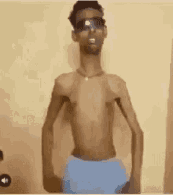 a shirtless man wearing sunglasses and blue underwear is standing in front of a yellow wall .