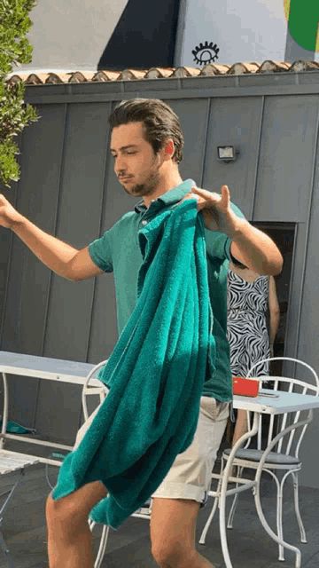 a man in a green shirt is holding a green towel over his shoulder
