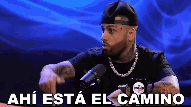 a man speaking into a microphone with the words " ahi esta el camino " above him