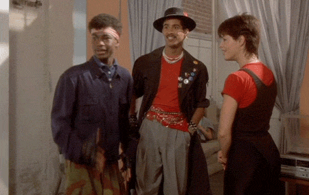 a man wearing a hat and a red shirt is standing next to two other people