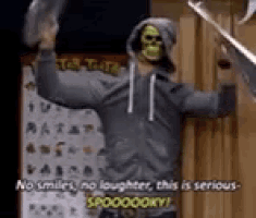 a man in a hoodie with a skeleton mask is holding a sword .