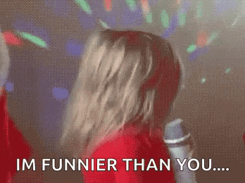 a woman in a red dress is holding a microphone and saying `` im funnier than you ... '' .