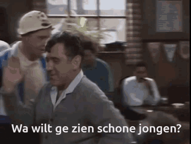 two men are dancing in a room with the words wa wilt ge zien schone jongen written on the bottom .