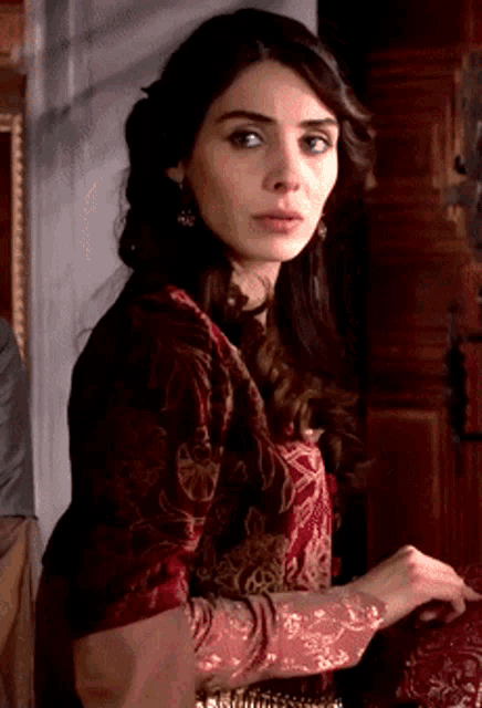 a woman in a red and black dress stands in front of a wooden door