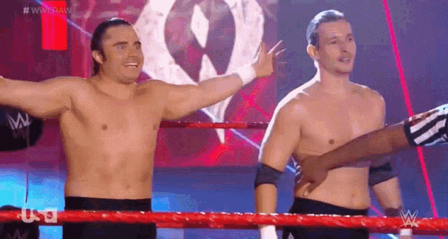 two wrestlers are standing in a ring with their arms outstretched