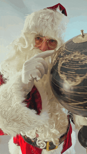 santa claus is pointing at a globe while wearing glasses and gloves