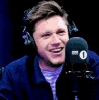a man wearing headphones is talking into a microphone .