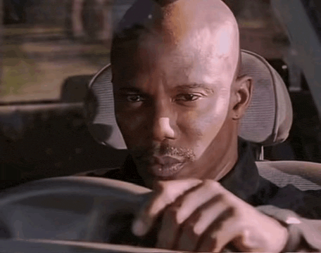 a man is driving a car and looking at the camera .