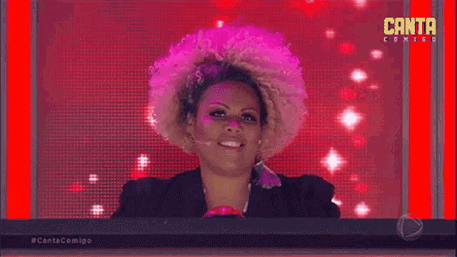 a woman singing in front of a screen with canta written on it