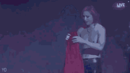 a shirtless man is standing on a stage holding a red jacket .