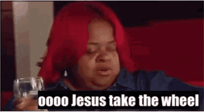 a woman with red hair is sitting at a table holding a glass of wine and making a funny face .