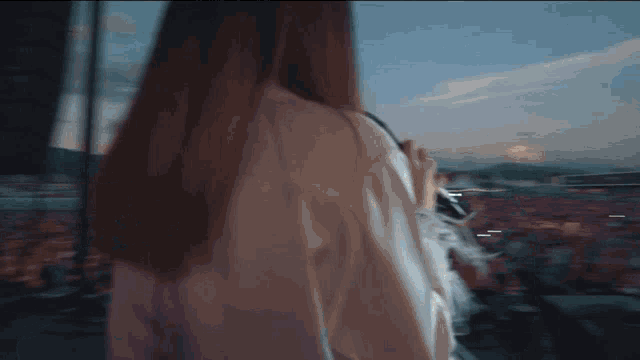 a woman in a white shirt is looking out a window at a crowd