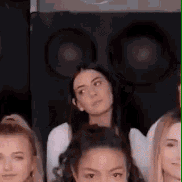 a group of women are sitting in front of a speaker and looking at the camera .